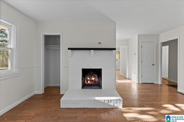 unfurnished living room with a fireplace, baseboards, and wood finished floors