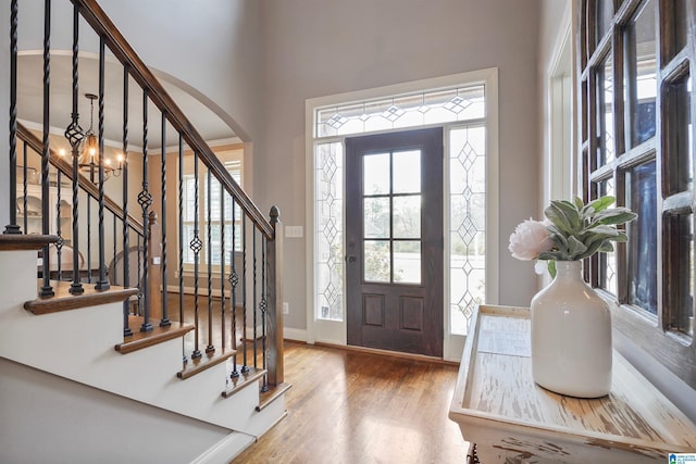 foyer with arched walkways, baseboards, and wood finished floors