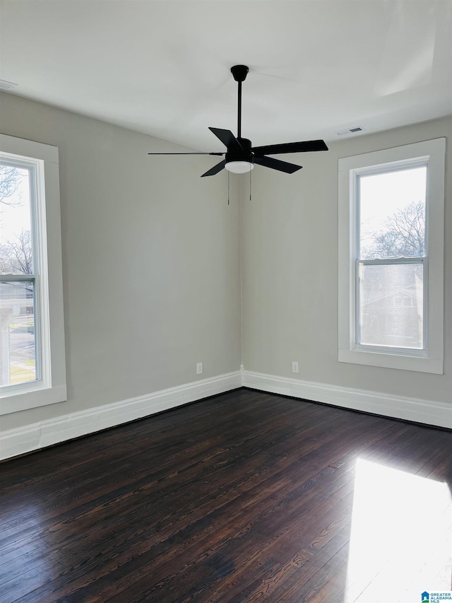 unfurnished room with visible vents, baseboards, a healthy amount of sunlight, and dark wood-style flooring