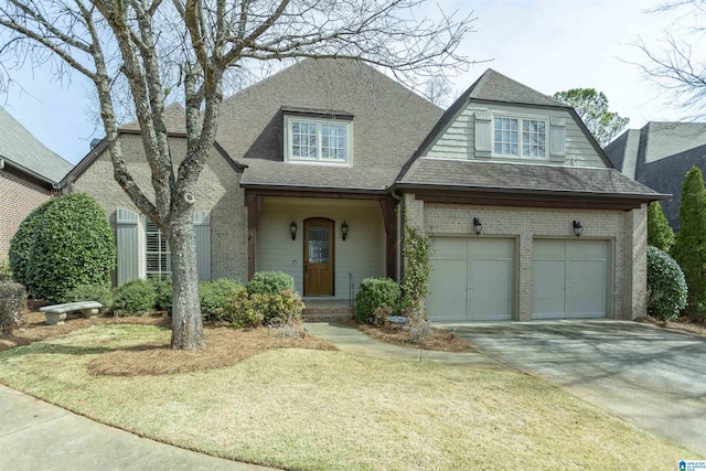 view of front facade featuring brick siding, a shingled roof, a garage, driveway, and a front lawn