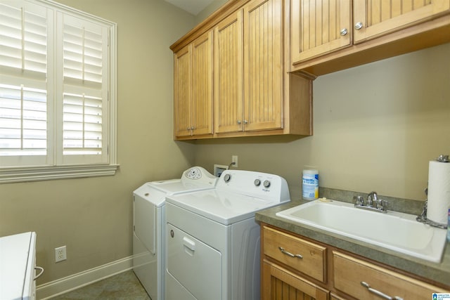 laundry area featuring separate washer and dryer, a sink, cabinet space, and baseboards