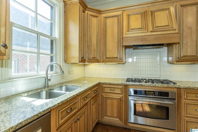 kitchen with brown cabinetry, appliances with stainless steel finishes, decorative backsplash, and a sink