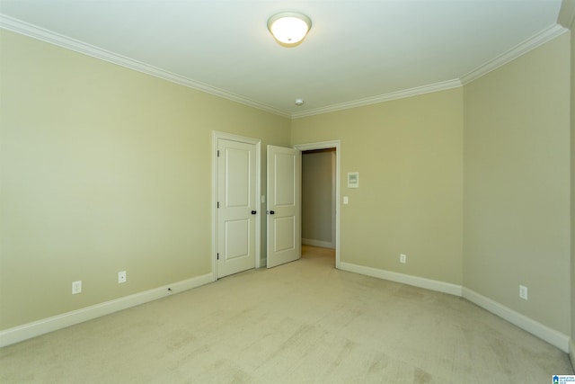 empty room featuring light carpet, baseboards, and crown molding