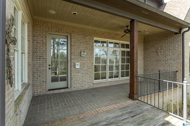 view of exterior entry with a ceiling fan and brick siding