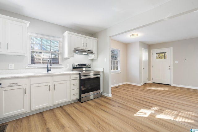 kitchen with under cabinet range hood, a sink, light wood-style floors, light countertops, and stainless steel electric range