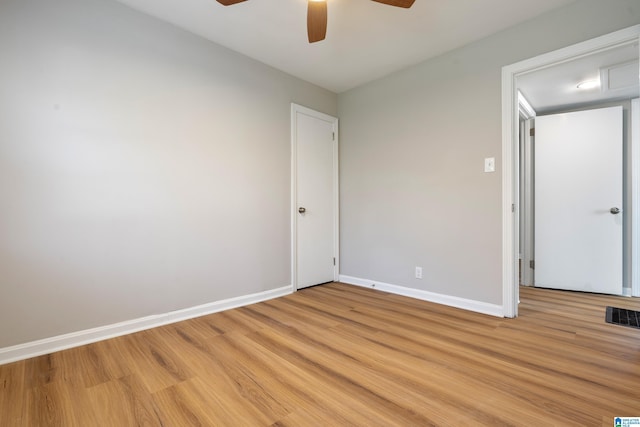 empty room with light wood finished floors, a ceiling fan, visible vents, and baseboards