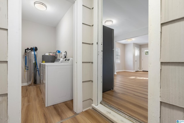 laundry area featuring laundry area, washing machine and clothes dryer, wood finished floors, and baseboards