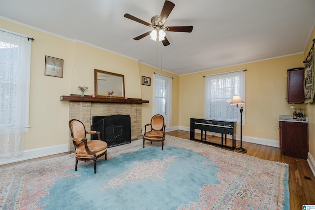 living area featuring ornamental molding, a fireplace, baseboards, and wood finished floors