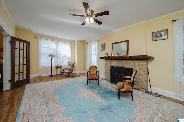 sitting room with baseboards, a fireplace, wood finished floors, and crown molding