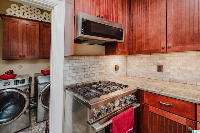 kitchen with light stone counters, stainless steel appliances, washer and dryer, dark brown cabinets, and tasteful backsplash