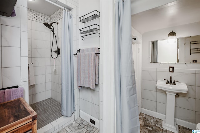 full bath with a shower stall, baseboards, and tile walls