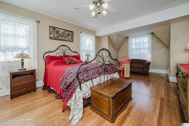 bedroom featuring ceiling fan, hardwood / wood-style floors, multiple windows, and baseboards