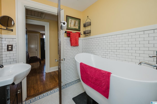 full bathroom featuring a wainscoted wall, a soaking tub, and tile walls