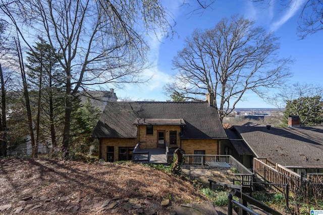 view of front facade with stone siding and a wooden deck