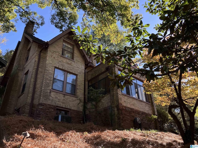 view of side of property with a chimney and brick siding