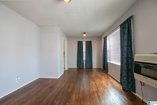 spare room with baseboards, heating unit, and hardwood / wood-style flooring