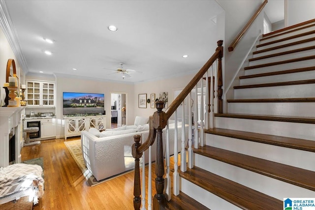 living area with a fireplace, recessed lighting, ornamental molding, light wood-style floors, and stairs