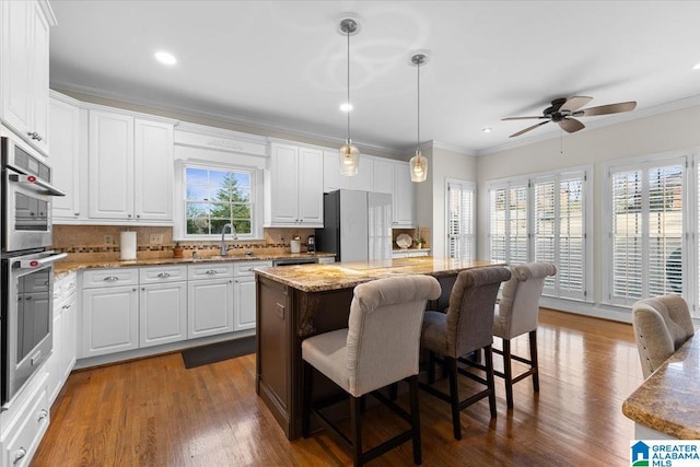 kitchen featuring a kitchen island, a sink, ornamental molding, freestanding refrigerator, and dark wood-style floors