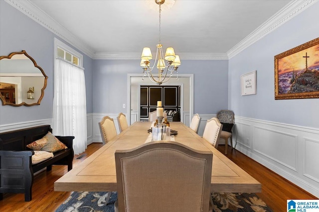 dining room with ornamental molding, wood finished floors, a wainscoted wall, and an inviting chandelier