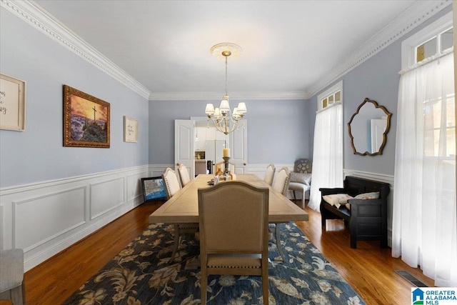 dining room featuring wood finished floors, a healthy amount of sunlight, visible vents, and an inviting chandelier