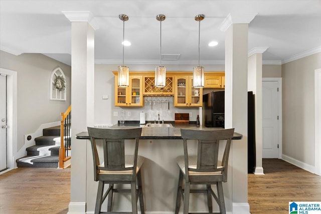 kitchen featuring wood finished floors, a breakfast bar, a sink, and black fridge with ice dispenser