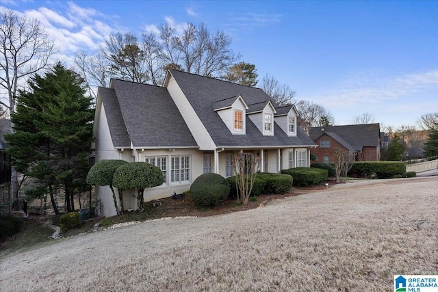 new england style home featuring roof with shingles and brick siding