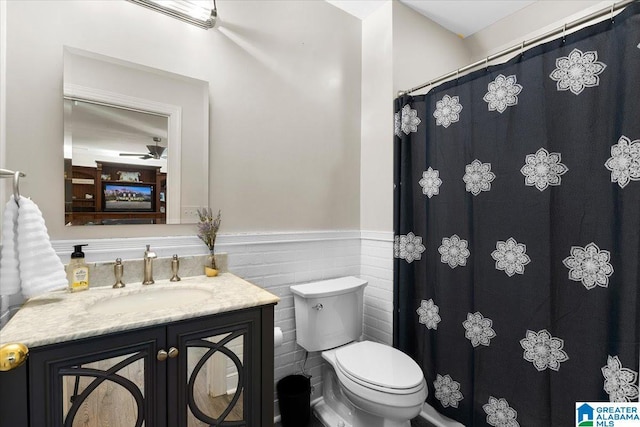 bathroom with wainscoting, vanity, toilet, and a shower with curtain