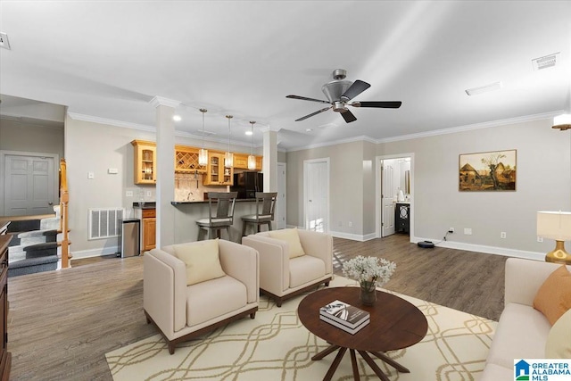 living area featuring light wood-type flooring, visible vents, and crown molding