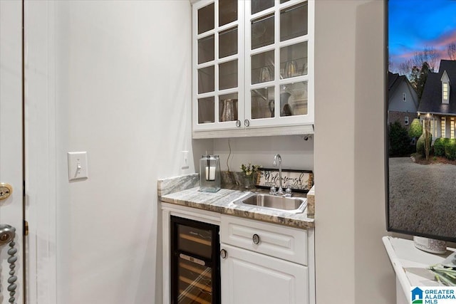 bar with beverage cooler, indoor wet bar, and a sink