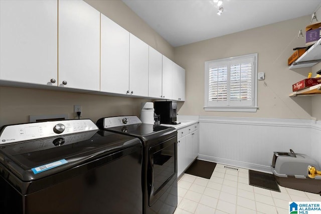 clothes washing area with cabinet space, washing machine and dryer, visible vents, and a wainscoted wall