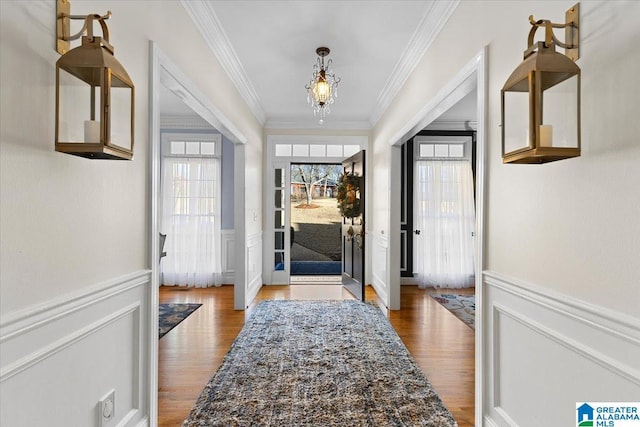 doorway with a wainscoted wall, wood finished floors, and a healthy amount of sunlight