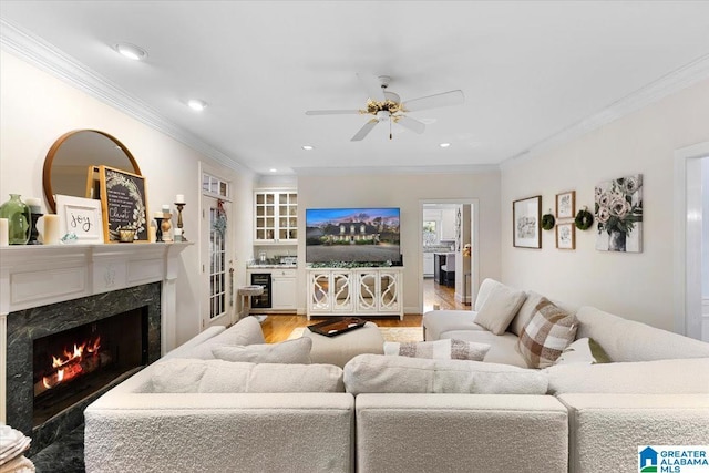 living area with ceiling fan, ornamental molding, wood finished floors, and a high end fireplace