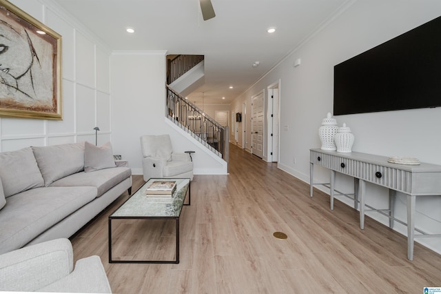 living area featuring ceiling fan, recessed lighting, light wood-style floors, ornamental molding, and stairway