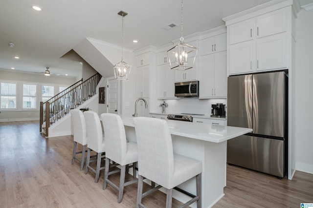 kitchen with visible vents, an island with sink, appliances with stainless steel finishes, a breakfast bar, and light countertops