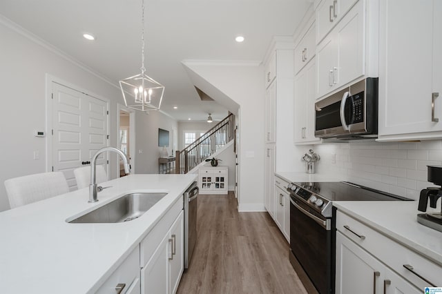 kitchen with stainless steel appliances, light countertops, decorative backsplash, light wood-style floors, and a sink