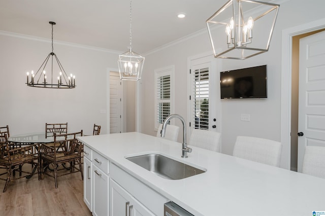 kitchen featuring an inviting chandelier, ornamental molding, light wood-style floors, white cabinetry, and a sink