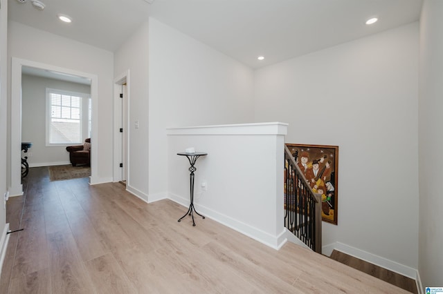 corridor with recessed lighting, baseboards, an upstairs landing, and wood finished floors