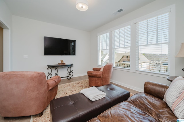 living room with plenty of natural light, wood finished floors, visible vents, and baseboards