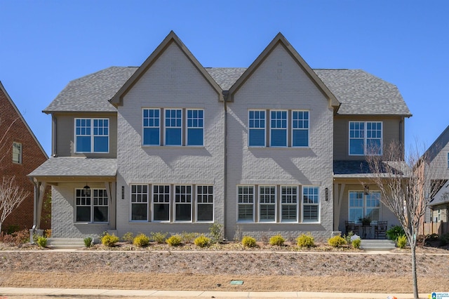 view of front facade with a shingled roof and brick siding