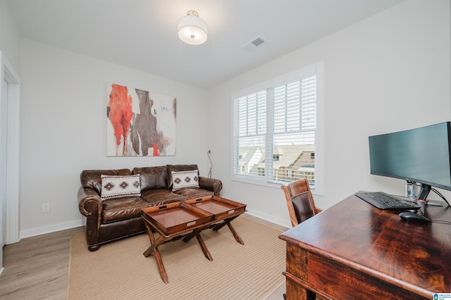 office space with light wood-type flooring, visible vents, and baseboards