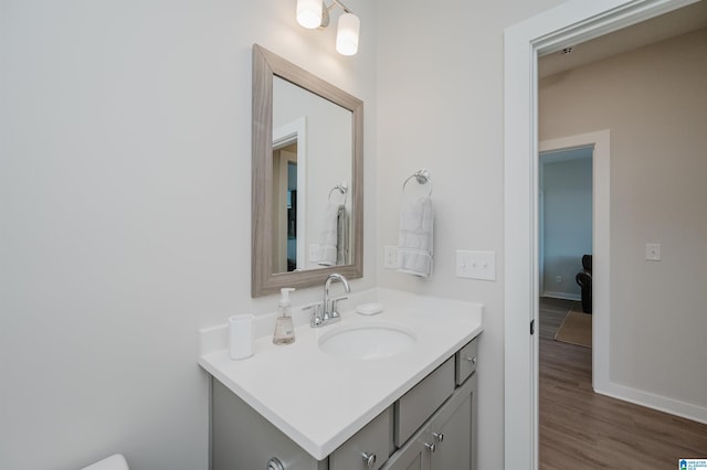 half bathroom with wood finished floors, vanity, and baseboards