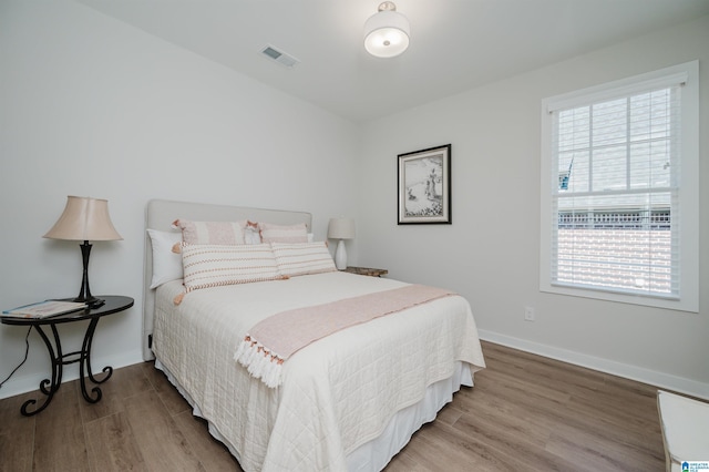 bedroom featuring wood finished floors, visible vents, and baseboards