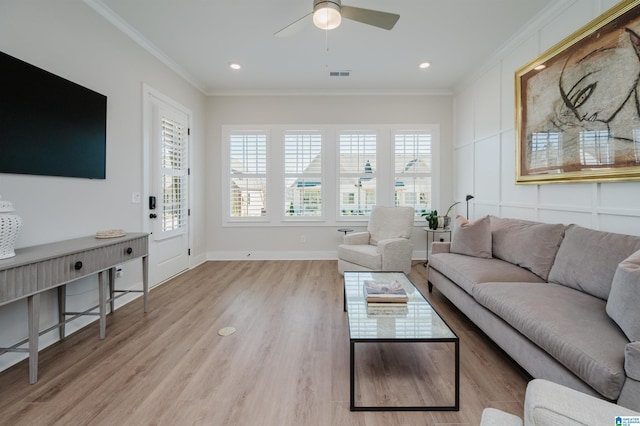 living area featuring ceiling fan, visible vents, baseboards, ornamental molding, and light wood finished floors