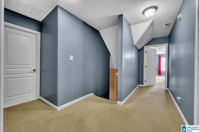 hallway with vaulted ceiling, an upstairs landing, baseboards, and carpet floors