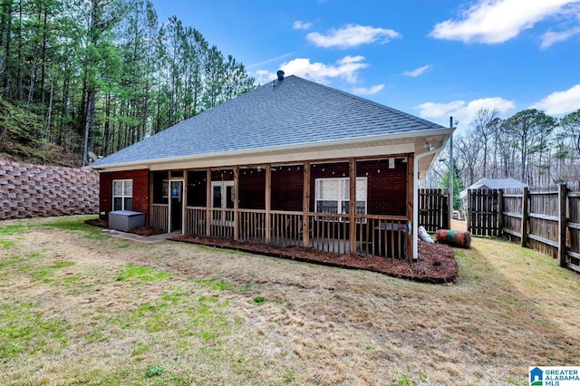 rear view of house with a yard, fence, and a shingled roof