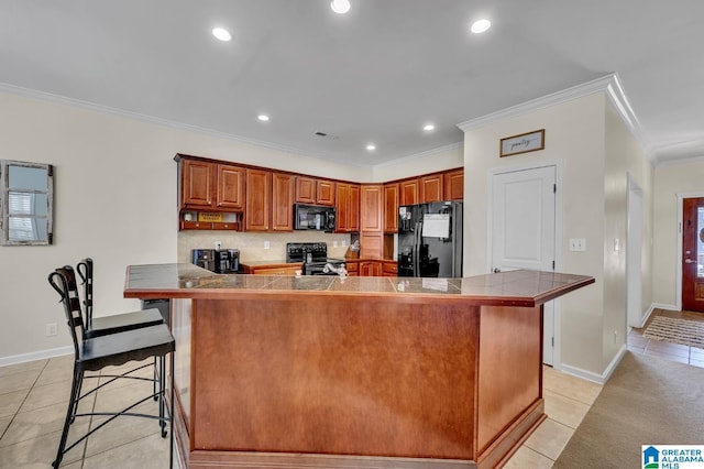 kitchen with a breakfast bar, black appliances, light tile patterned floors, and crown molding