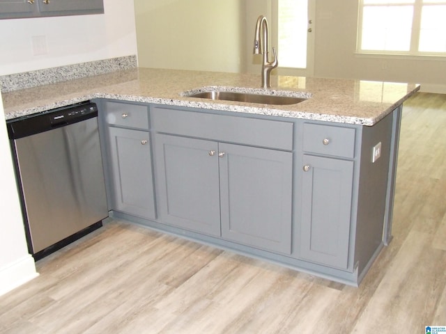 kitchen with light wood-style flooring, gray cabinetry, a sink, light stone countertops, and dishwasher