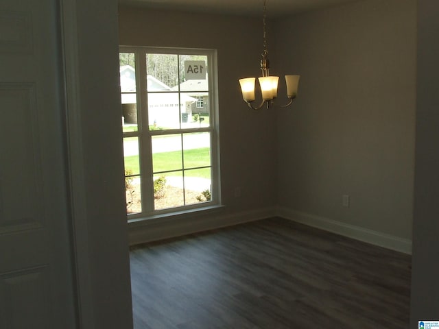 unfurnished room featuring baseboards, dark wood-style flooring, and a notable chandelier