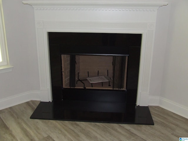 details with a fireplace with flush hearth, baseboards, and wood finished floors