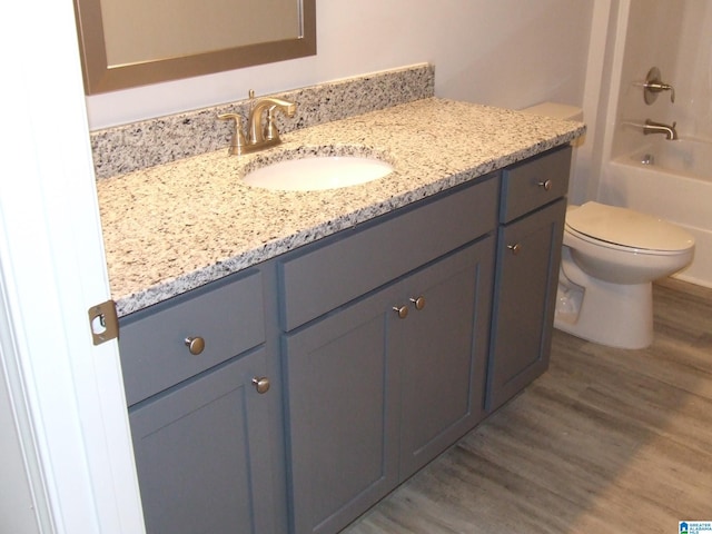 full bathroom with toilet, tub / shower combination, wood finished floors, and vanity